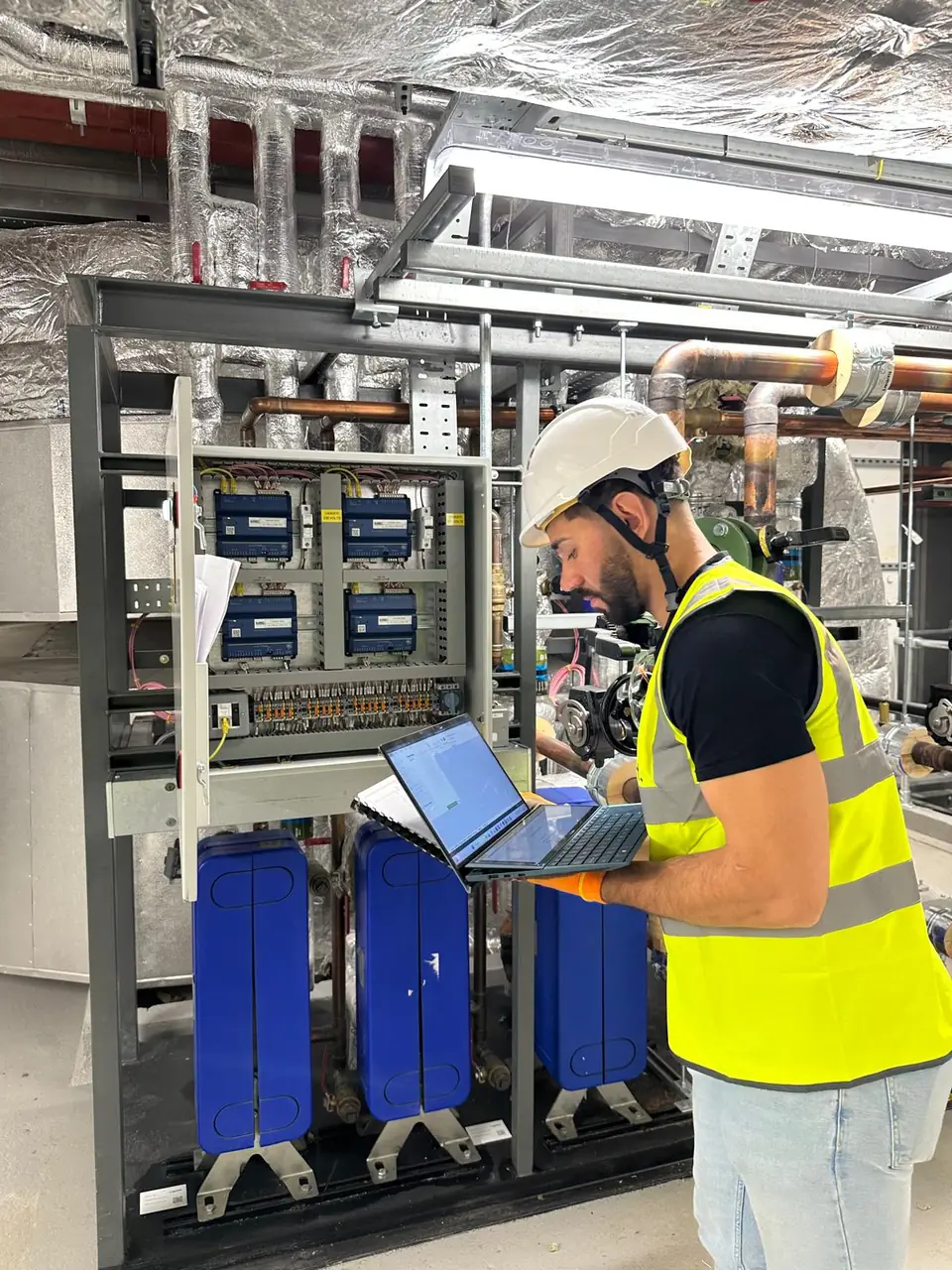 Engineer commissioning a BMS cabinet with Trend IQ controllers